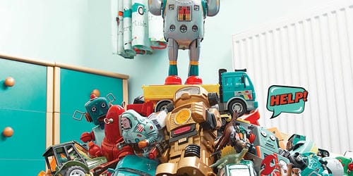 Various robot, construction vehicle, astronaut and dinosaur toys stack chaotically into an unruly heap; a comic “HELP!” bubble highlights the clutter from disorganized toy storage.