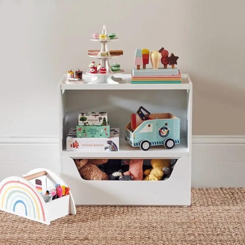 A white open storage shelf neatly organizes pretend food toys, puzzle boxes, toy truck and stuffed plush animals, with a small rainbow-shaped toy bin placed beside the cabinet for tidy toy management.
